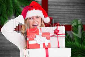 Composite image of festive blonde holding pile of gifts