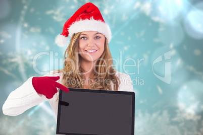 Composite image of festive blonde pointing to laptop