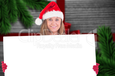 Composite image of festive blonde holding a poster