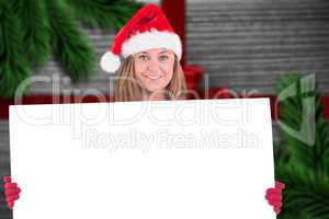 Composite image of festive blonde holding a poster