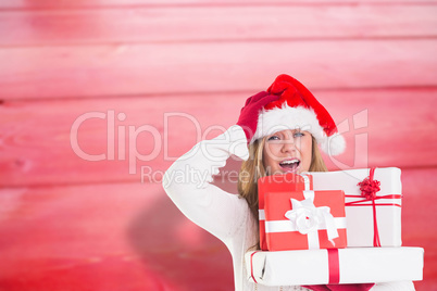 Composite image of festive blonde holding pile of gifts