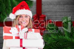 Composite image of festive blonde holding pile of gifts