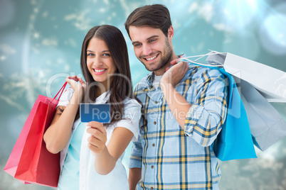 Composite image of couple with shopping bags and credit card