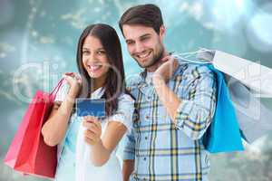 Composite image of couple with shopping bags and credit card