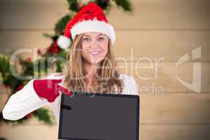 Composite image of festive blonde pointing to laptop