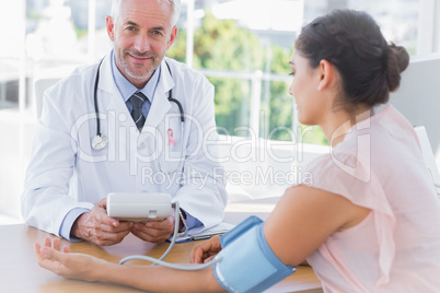 Composite image of smiling doctor taking the heartbeat of a pati
