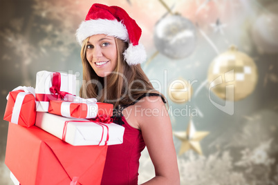 Composite image of festive blonde holding pile of gifts