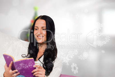 Composite image of smiling woman reading a book