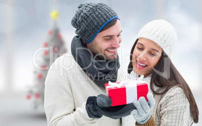 Composite image of winter couple holding gift