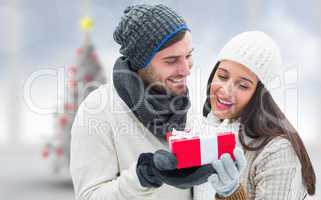 Composite image of winter couple holding gift