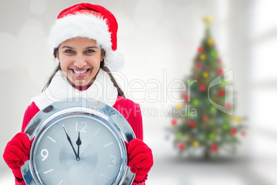 Composite image of festive brunette holding clock