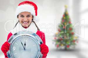 Composite image of festive brunette holding clock