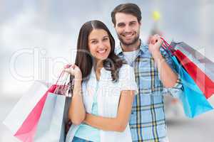 Composite image of happy couple with shopping bags