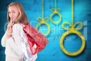 Composite image of pretty blonde keeping a secret holding bags