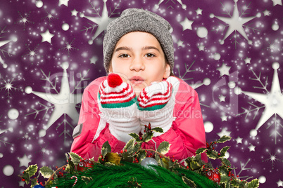 Composite image of wrapped up little girl blowing over hands