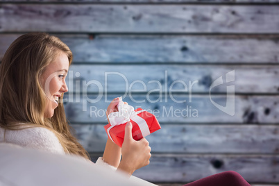 Composite image of pretty blonde relaxing on the couch with gift