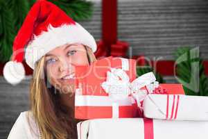 Composite image of festive blonde holding pile of gifts