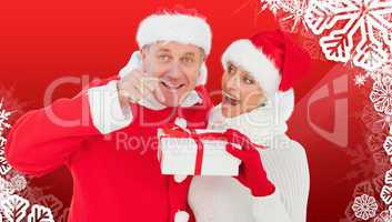 Composite image of festive mature couple holding gift