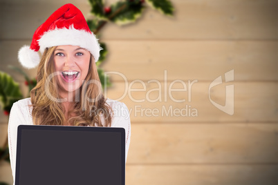 Composite image of festive blonde showing a laptop