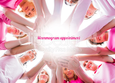 Diverse women smiling in circle wearing pink for breast cancer