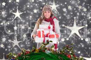 Composite image of happy blonde in winter clothes holding gifts