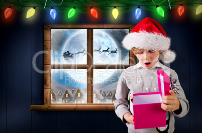 Composite image of festive boy holding a gift