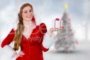 Composite image of pretty girl in santa costume holding gift box