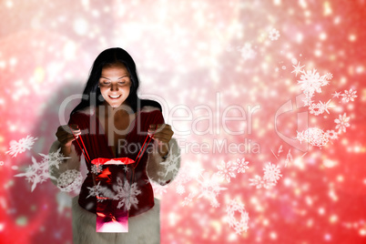 Composite image of smiling woman opening christmas present