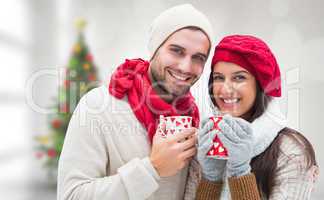 Composite image of winter couple holding mugs