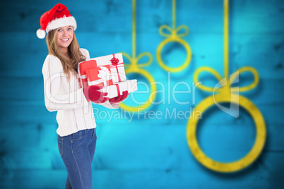 Composite image of festive blonde holding pile of gifts