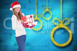 Composite image of festive blonde holding pile of gifts