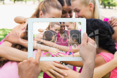 Composite image of hand holding tablet pc