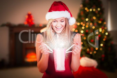 Composite image of festive blonde opening a gift bag