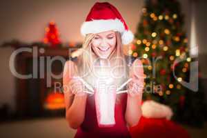 Composite image of festive blonde opening a gift bag