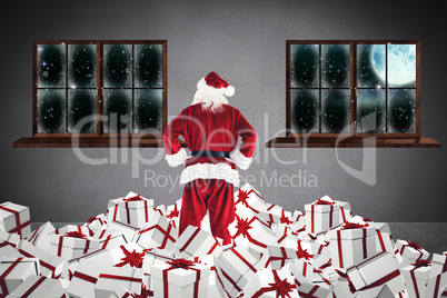 Composite image of santa standing on pile of gifts