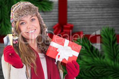 Composite image of happy blonde in winter clothes holding gifts
