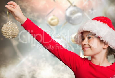 Composite image of festive girl hanging decoration