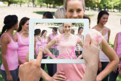 Composite image of hand holding tablet pc