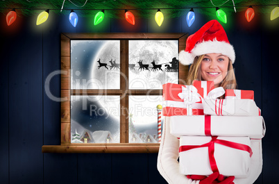 Composite image of festive blonde holding pile of gifts