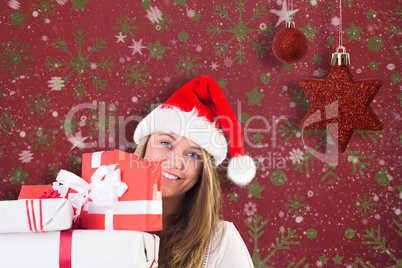 Composite image of festive blonde holding pile of gifts