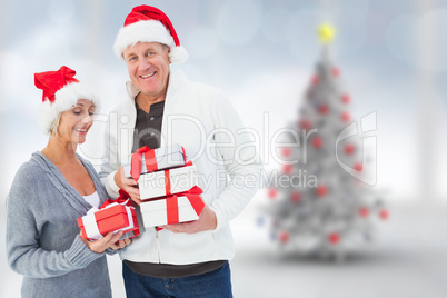 Composite image of festive mature couple holding christmas gifts