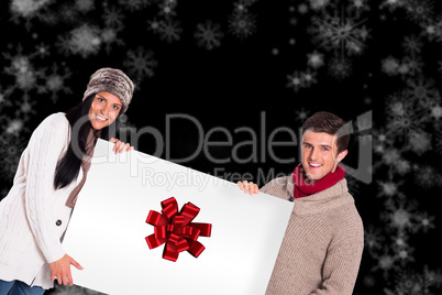 Composite image of young couple holding a poster