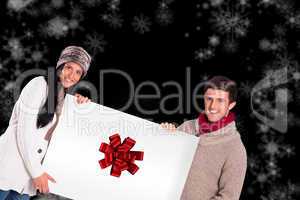 Composite image of young couple holding a poster