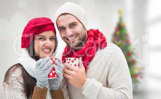 Composite image of winter couple holding mugs