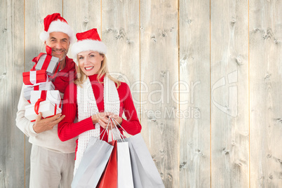 Composite image of happy festive couple with gifts and bags