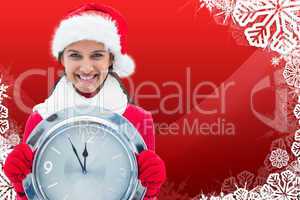 Composite image of festive brunette holding clock