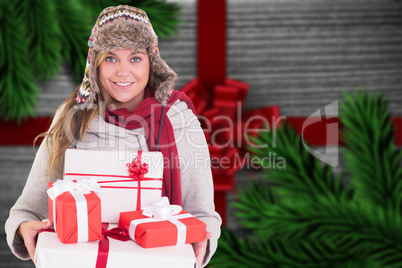 Composite image of happy blonde in winter clothes holding gifts Composite image of happy blonde in winter clothes holding gifts