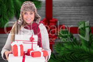 Composite image of happy blonde in winter clothes holding gifts