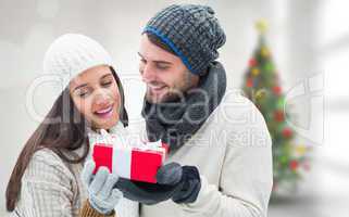 Composite image of winter couple holding gift