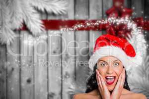 Composite image of surprised woman wearing santa hat